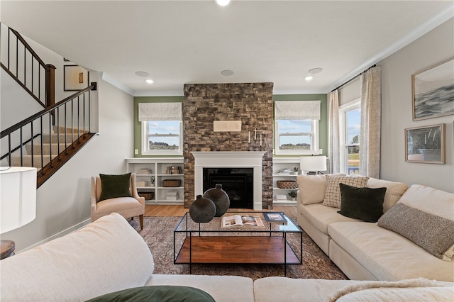 living room with hardwood / wood-style floors, crown molding, and a stone fireplace