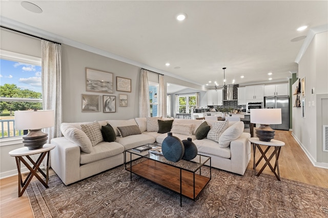 living room featuring light wood-type flooring, crown molding, and a notable chandelier