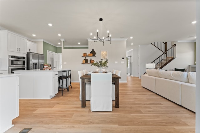 dining space with ornamental molding, a chandelier, and light hardwood / wood-style flooring