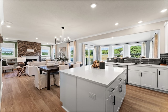 kitchen with a multi sided fireplace, a healthy amount of sunlight, a kitchen island, and light hardwood / wood-style floors