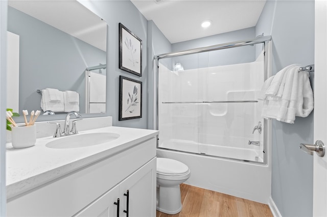 full bathroom with hardwood / wood-style floors, toilet, bath / shower combo with glass door, and vanity