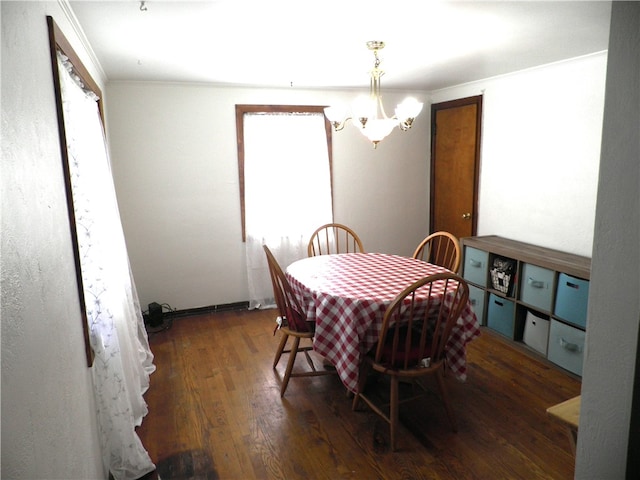 dining area with ornamental molding, a chandelier, and dark hardwood / wood-style flooring