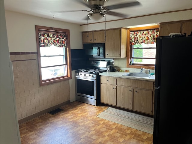 kitchen featuring ceiling fan, sink, light parquet flooring, black appliances, and tile walls