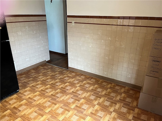 unfurnished room with tile walls and light parquet flooring