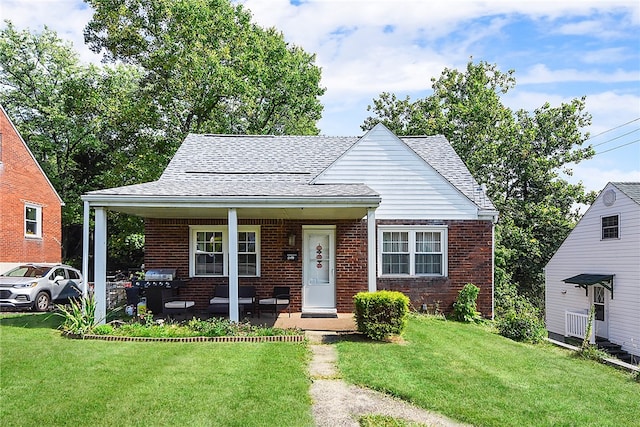 bungalow-style house featuring covered porch and a front yard