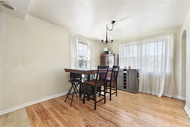 dining area featuring a textured ceiling, light hardwood / wood-style flooring, and a chandelier