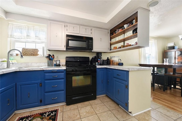 kitchen featuring black appliances, a sink, blue cabinetry, light countertops, and light tile patterned flooring