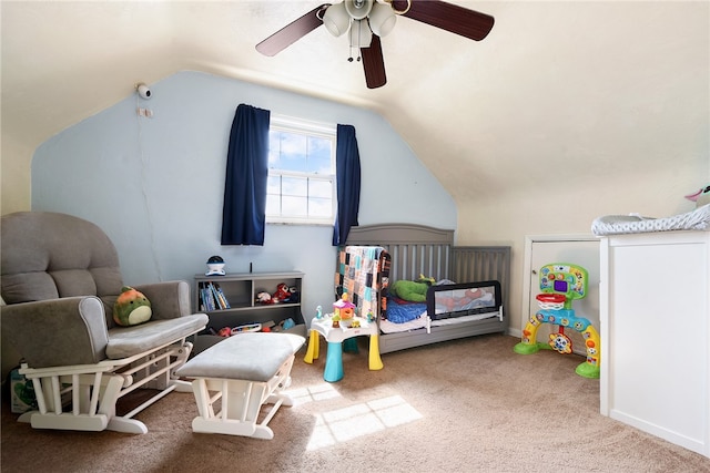 carpeted bedroom featuring lofted ceiling, ceiling fan, and a crib