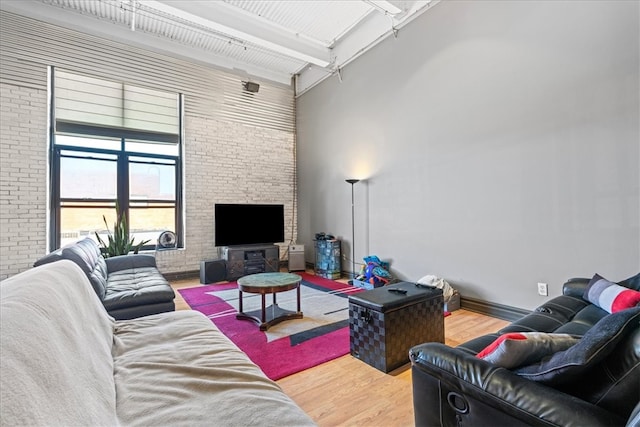 living room featuring a fireplace, high vaulted ceiling, hardwood / wood-style flooring, brick wall, and beam ceiling