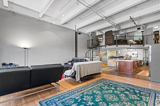 bedroom featuring a towering ceiling, wood-type flooring, and stainless steel refrigerator