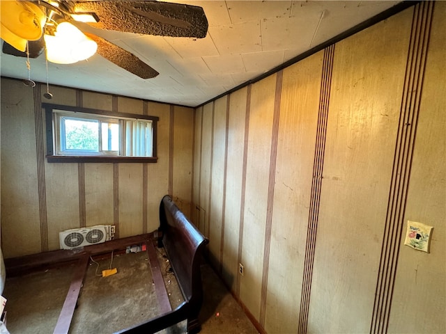 interior space with ceiling fan and wood walls