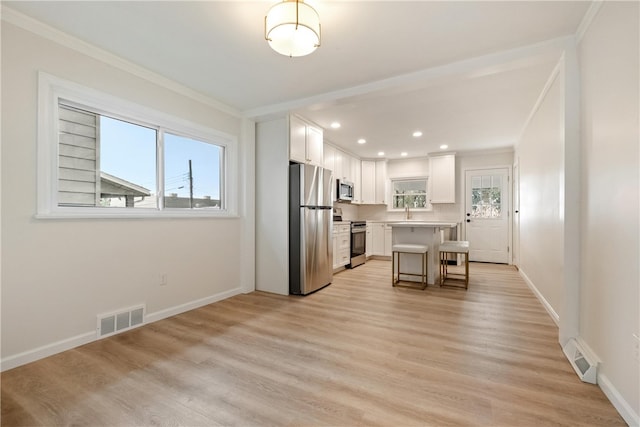 kitchen featuring a kitchen bar, a center island, stainless steel appliances, and a wealth of natural light