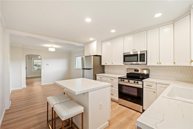 kitchen with a center island, crown molding, stainless steel appliances, white cabinetry, and a breakfast bar