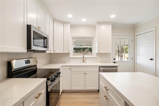 kitchen featuring white cabinets, stainless steel appliances, crown molding, and light hardwood / wood-style flooring