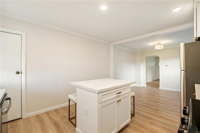 kitchen with light hardwood / wood-style floors, white cabinetry, a kitchen bar, a kitchen island, and ornamental molding