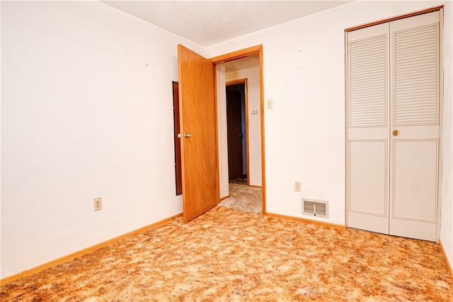 unfurnished bedroom featuring light carpet and a closet