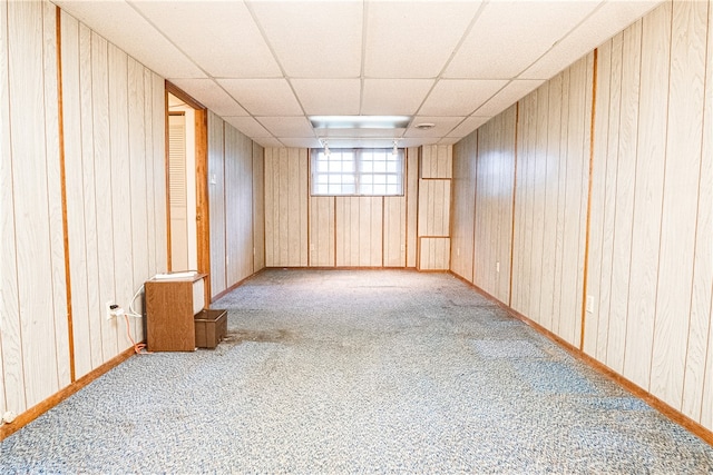 unfurnished room with carpet floors, a paneled ceiling, and wooden walls