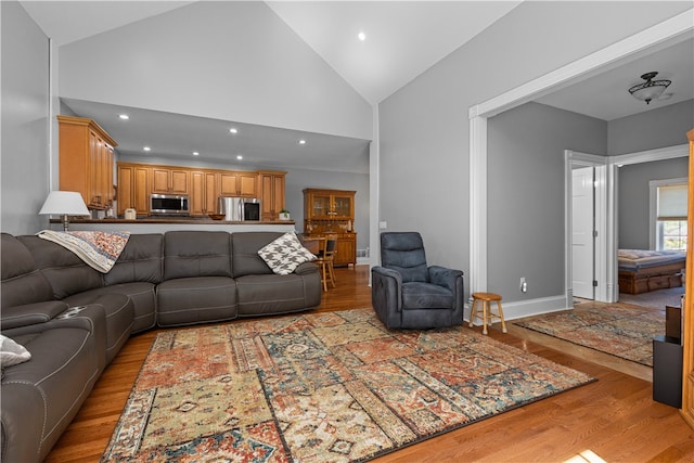 living room featuring high vaulted ceiling and light wood-type flooring