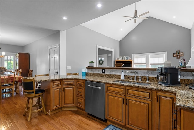 kitchen featuring sink, stainless steel dishwasher, high vaulted ceiling, ceiling fan with notable chandelier, and light hardwood / wood-style floors