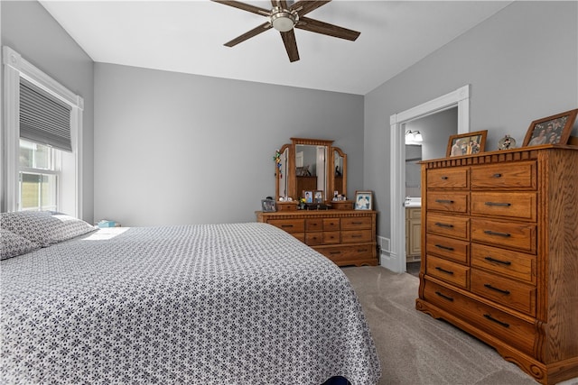 carpeted bedroom with ceiling fan and ensuite bath