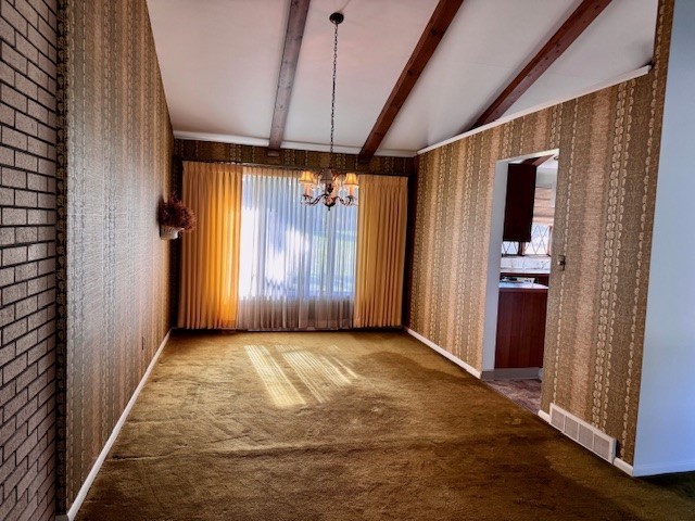 unfurnished dining area featuring vaulted ceiling with beams, a chandelier, and carpet flooring