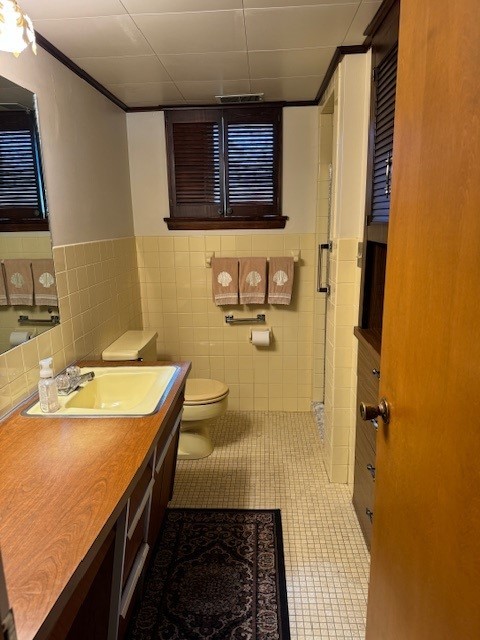 bathroom featuring tile walls, toilet, a shower with shower door, vanity, and tile patterned flooring