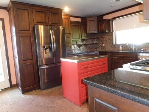 kitchen with dark stone counters, a center island, backsplash, light tile patterned floors, and stainless steel fridge