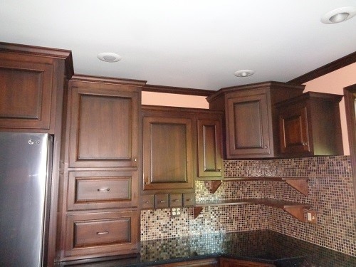 kitchen with stainless steel refrigerator, ornamental molding, and decorative backsplash