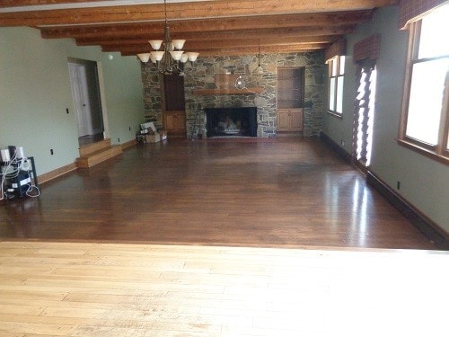 unfurnished living room with light wood-type flooring, beamed ceiling, plenty of natural light, and a stone fireplace