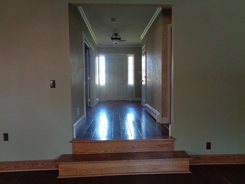 hallway featuring a baseboard radiator, crown molding, and dark wood-type flooring