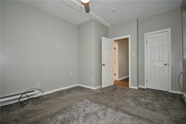 unfurnished bedroom with baseboard heating, ceiling fan, dark colored carpet, and a textured ceiling