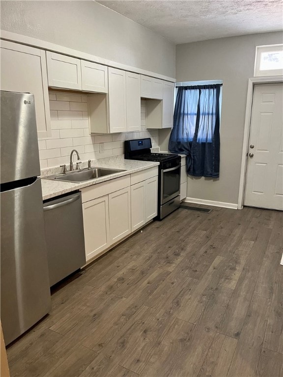 kitchen featuring a textured ceiling, dark hardwood / wood-style floors, stainless steel appliances, sink, and white cabinets