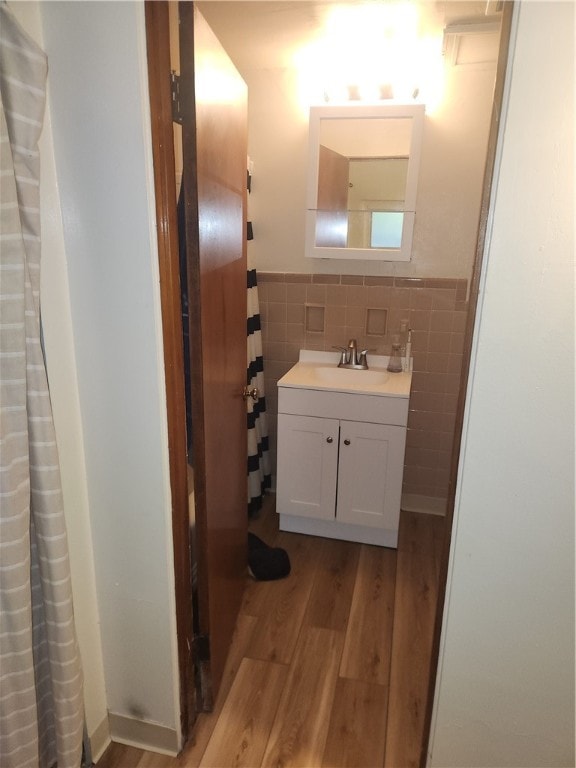 bathroom featuring wood-type flooring, walk in shower, vanity, and tile walls