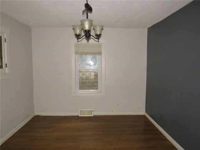 unfurnished dining area featuring a notable chandelier and dark hardwood / wood-style flooring