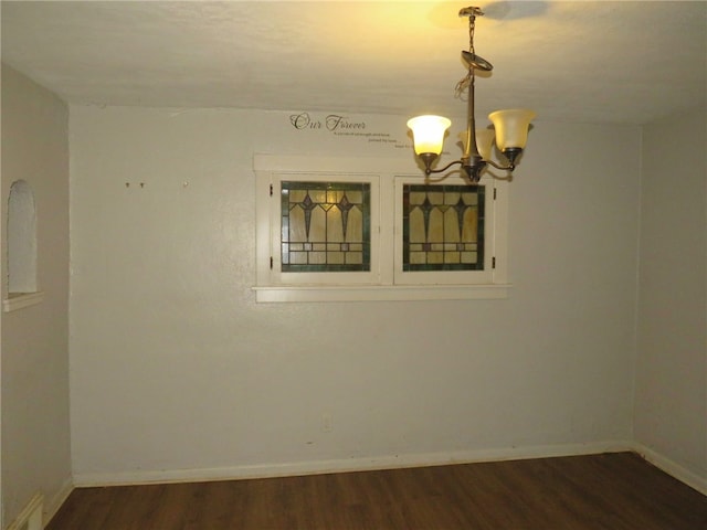 empty room with a chandelier and dark wood-type flooring