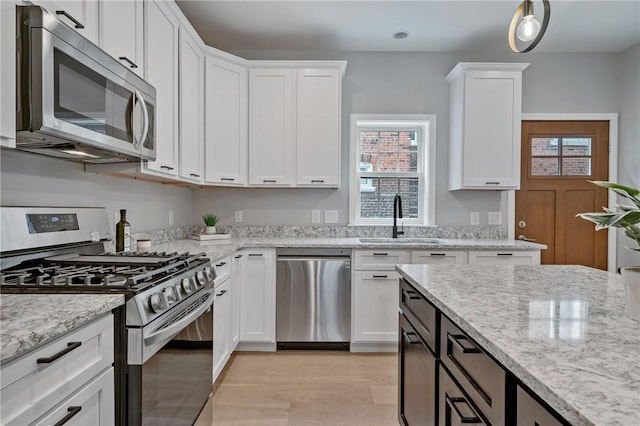 4602 Davison St, Lawrenceville, PA 15201 - kitchen with appliances with stainless steel finishes, a sink, white cabinetry, and plenty of natural light