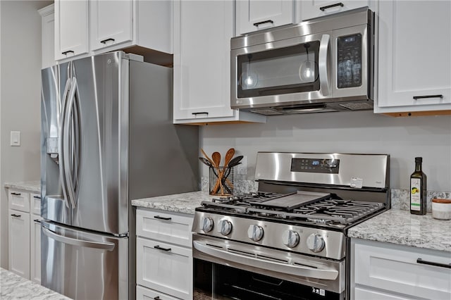 kitchen with appliances with stainless steel finishes, light stone countertops, and white cabinets