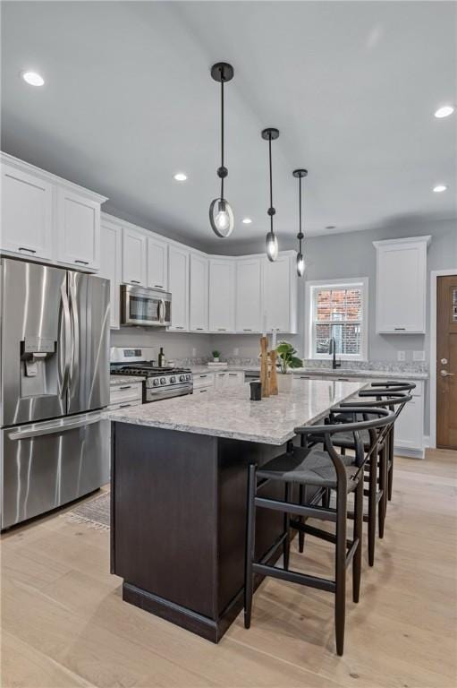 4602 Davison St, Lawrenceville, PA 15201 - kitchen featuring stainless steel appliances, recessed lighting, a center island, white cabinets, and light stone countertops