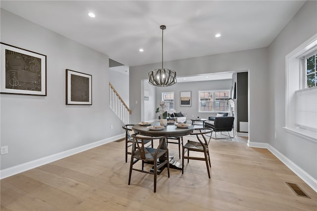 dining room with a wealth of natural light, an inviting chandelier, and light hardwood / wood-style flooring