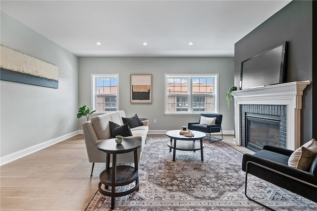 living room with a brick fireplace and light hardwood / wood-style floors