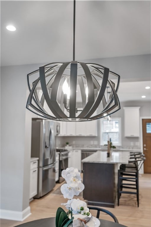 interior details with light hardwood / wood-style flooring, a kitchen island, stainless steel appliances, and white cabinets