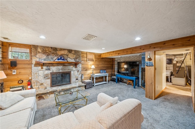 living room featuring a fireplace, light carpet, wood walls, and a textured ceiling