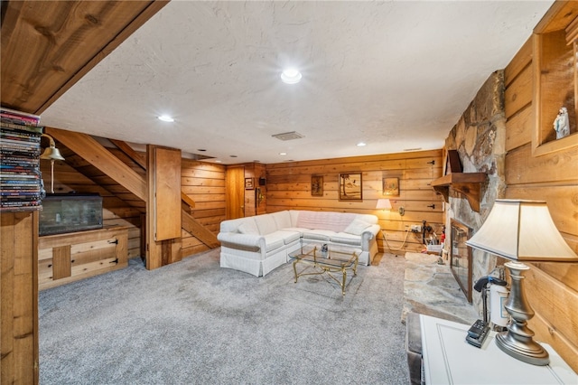 unfurnished living room with a fireplace, a textured ceiling, carpet floors, and wooden walls