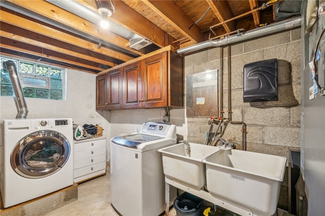 clothes washing area with separate washer and dryer, cabinets, and sink