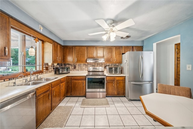 kitchen featuring light tile patterned floors, backsplash, stainless steel appliances, sink, and ceiling fan