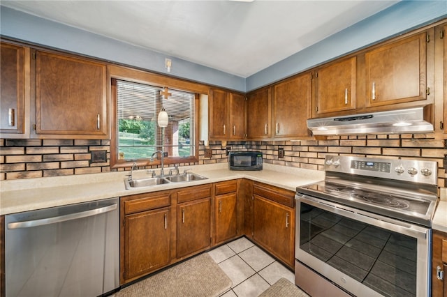 kitchen with appliances with stainless steel finishes, backsplash, light tile patterned flooring, and sink