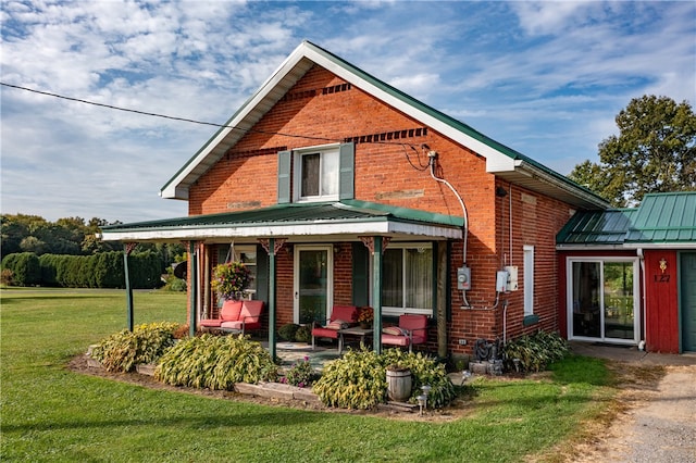 rear view of property with covered porch and a yard