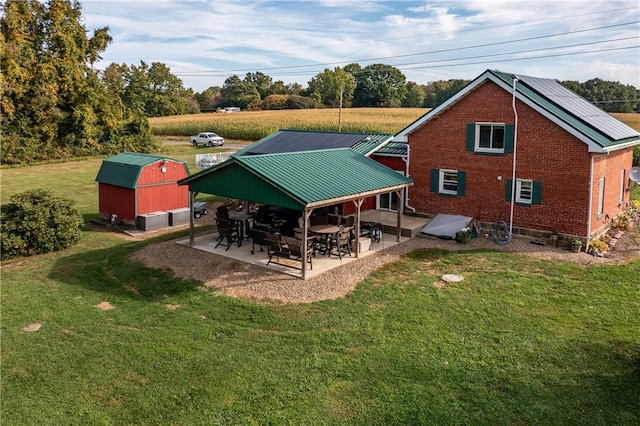 back of property featuring a lawn, a patio, and a shed