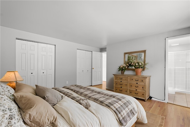 bedroom featuring two closets, light hardwood / wood-style floors, and ensuite bathroom