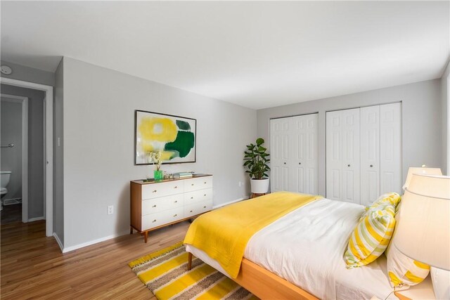 bedroom with multiple closets, light wood-type flooring, and connected bathroom